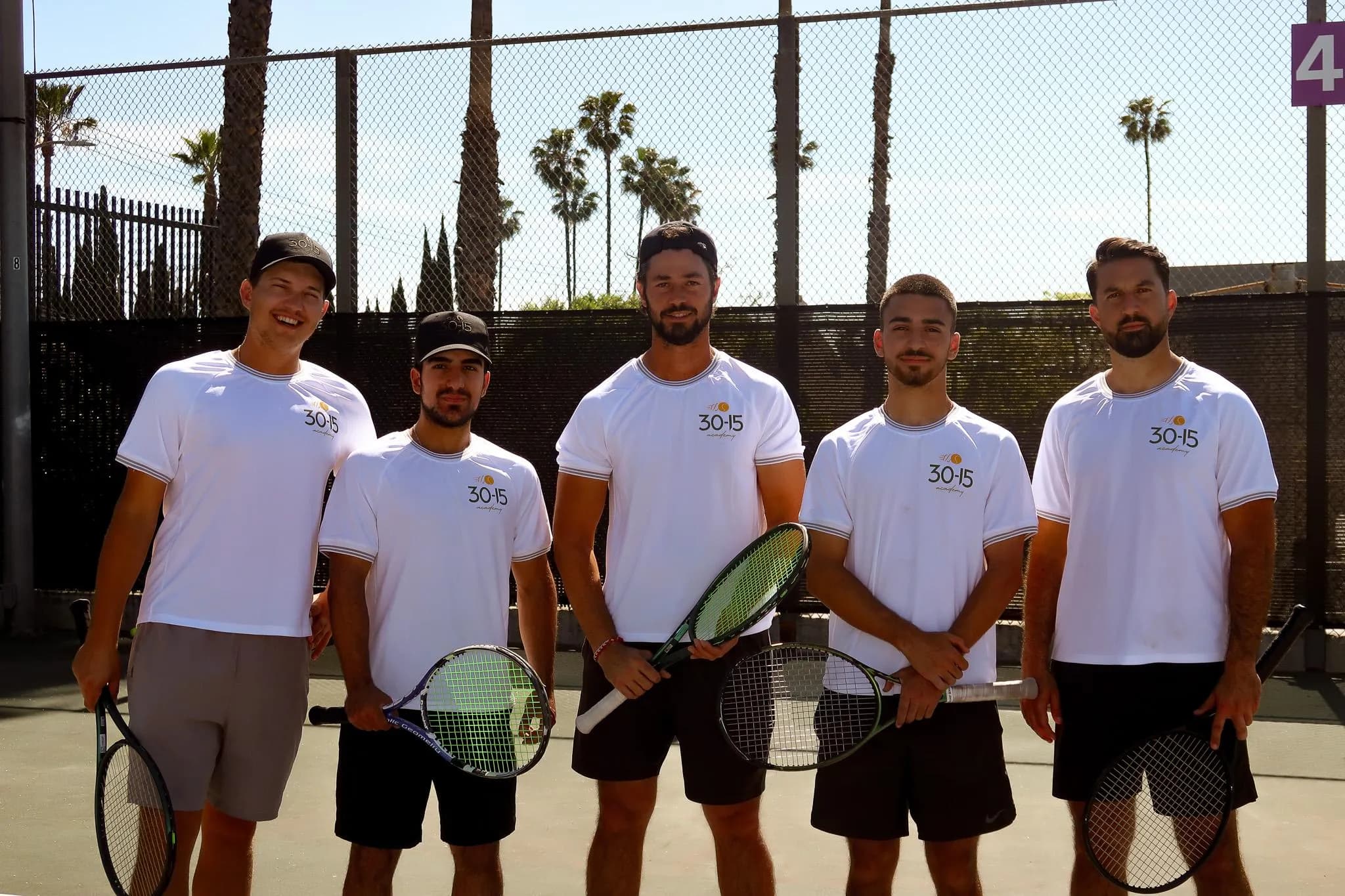 30-15 Tennis Academy coaching team posing with tennis rackets on outdoor courts in Glendale.