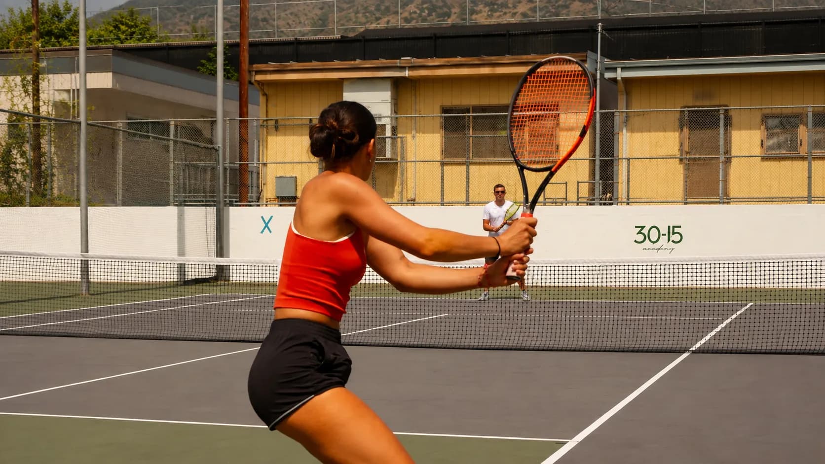 Couple practicing tennis during a couples lesson on an outdoor court in Glendale.